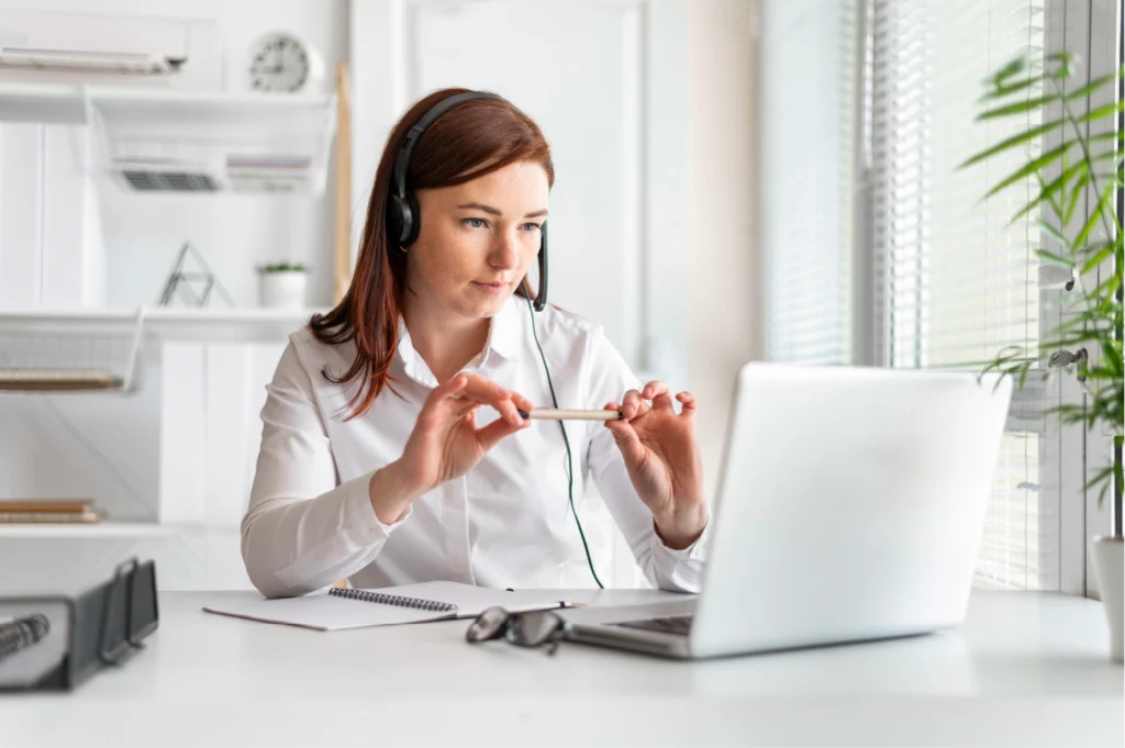 Mujer con auricular de call center trabajando frente a un portátil, proporcionando atención al cliente